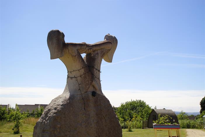A large stone sculpture in the garden at Russell House. It depicts two females facing each other, holding hands and leaning backwards, both facing up to the sky