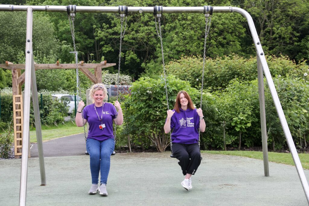 2 white female members of Forget Me Not staff sat on swings in the garden at Russell House