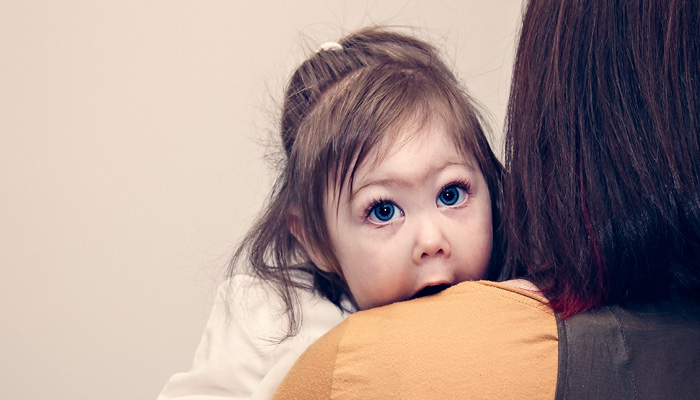 Picture of little girl looking over her mothers shoulder.