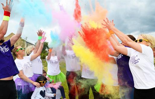 charity event showing people throwing coloured powder over themselves for the Colour Run event.