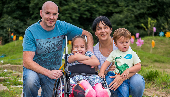 Mother, father and two children, a son and daughter smiling in the Hospice garden.