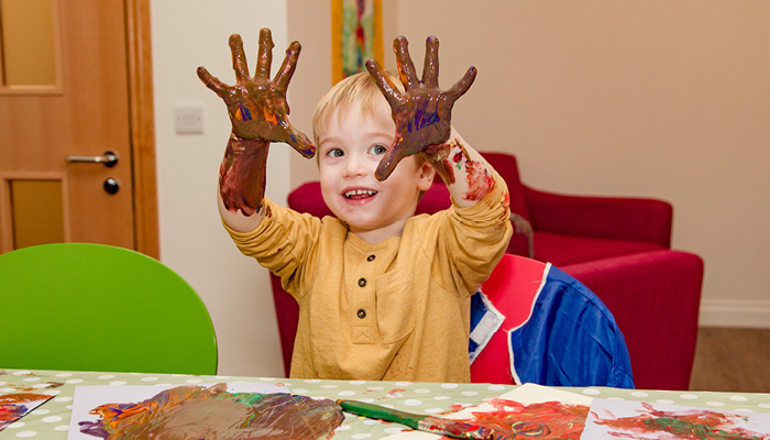 Child hand painting showing his paint covered hands.